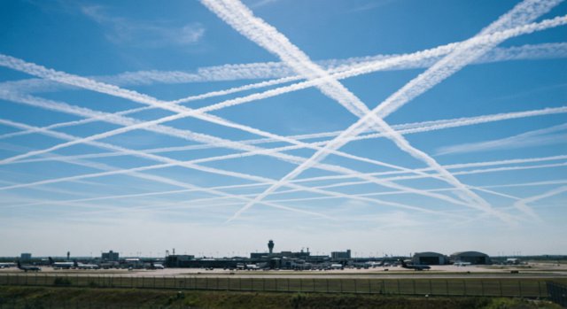 Kondensstreifen am blauen Himmel, die sich an einem Navigationspunkt kreuzen